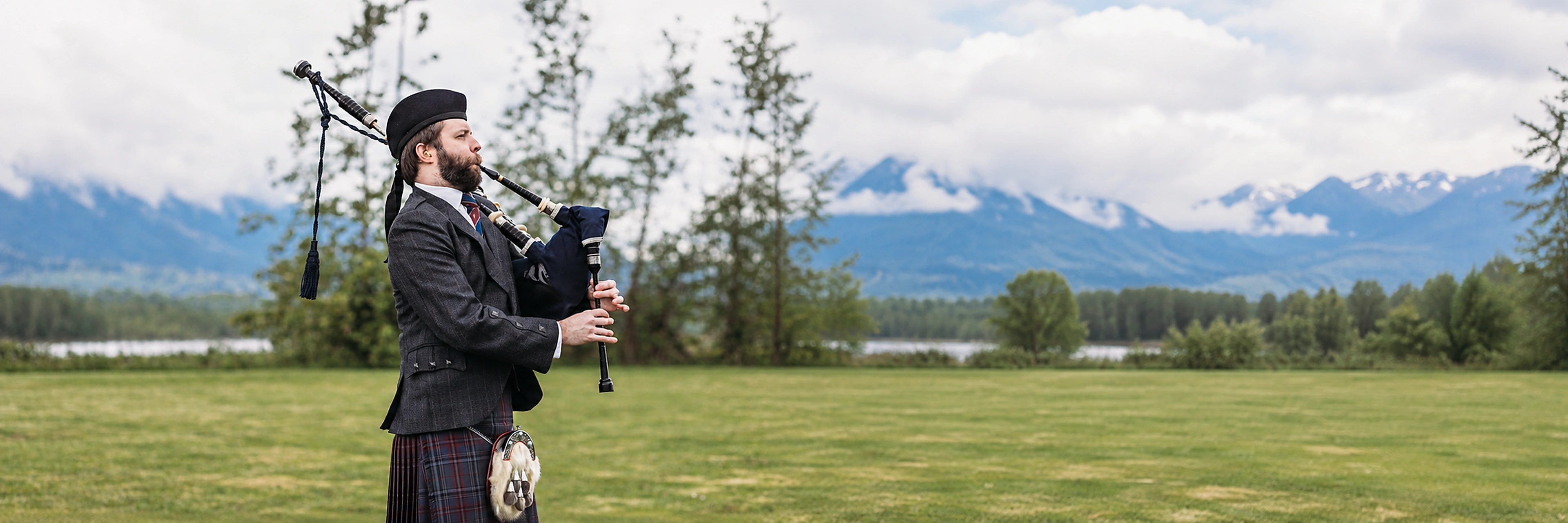 Alastair Lee playing Highland bagpipes with mountain scenery